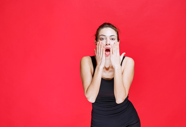 Foto gratuita chica de camisa negra sosteniendo su cabeza y reaccionando como un tonto. foto de alta calidad