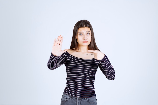 Foto gratuita chica con camisa a rayas apuntando a alguien del lado izquierdo.