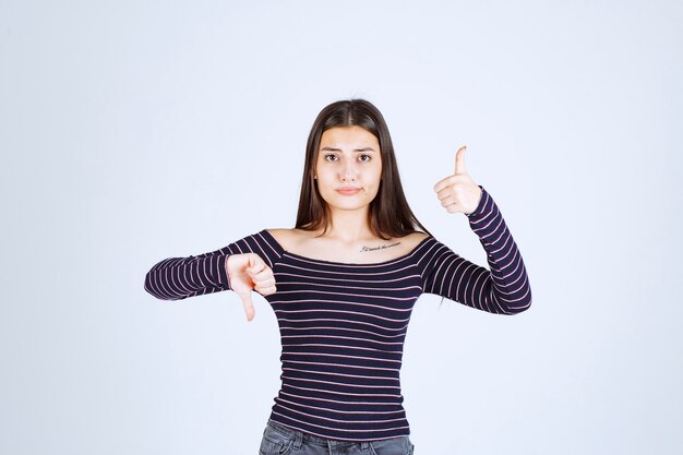 Chica en camisa a rayas haciendo señal de disfrute.