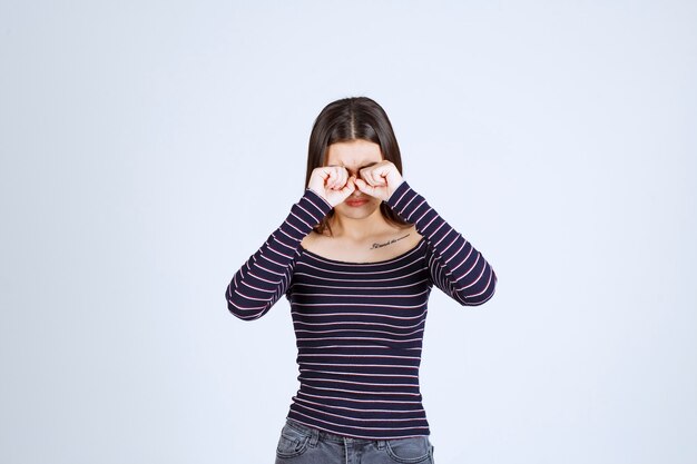 Foto gratuita chica en camisa a rayas mirando a través de sus dedos.
