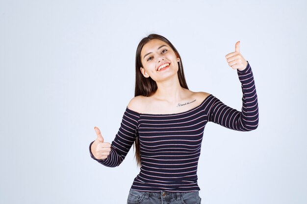 Chica en camisa a rayas mostrando buen signo de disfrute.