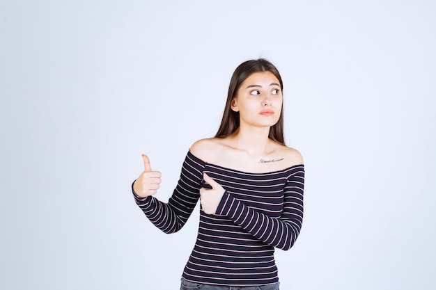 Chica en camisa a rayas mostrando buen signo de disfrute.