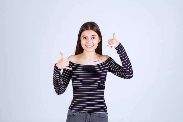 Foto gratuita chica en camisa a rayas mostrando distintivo de llamada.