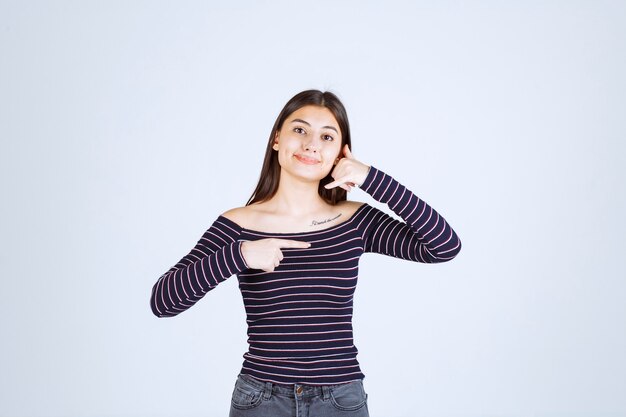 Chica en camisa a rayas mostrando el lado derecho y pidiendo llamada.