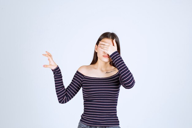 Chica en camisa de rayas mostrando la medida o cantidad estimada de un producto.