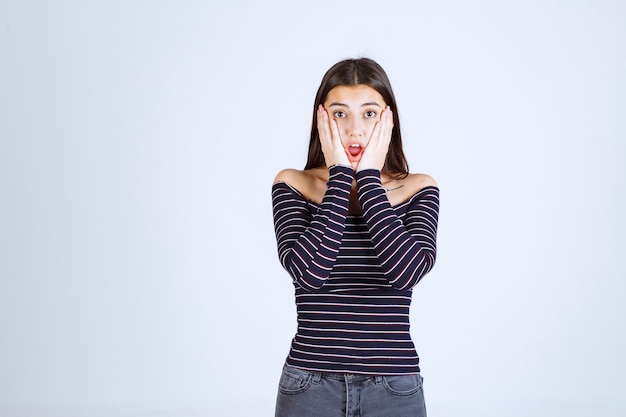 Chica con camisa a rayas parece aterrorizada y asustada.