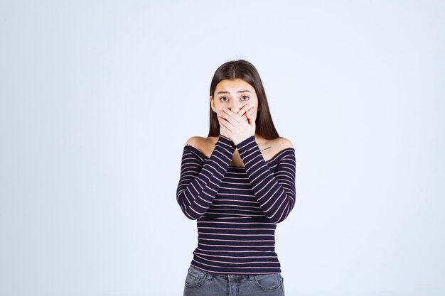 Chica con camisa a rayas parece aterrorizada y asustada.