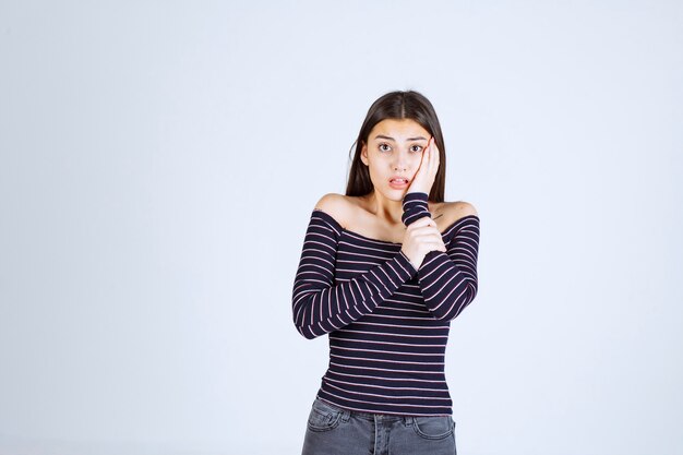 Chica con camisa a rayas parece aterrorizada y asustada.