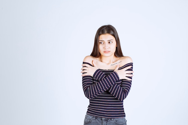 Chica con camisa a rayas parece aterrorizada y asustada.