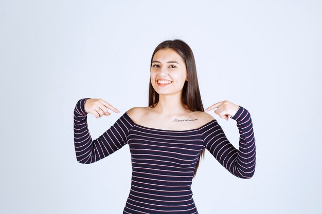 Chica en camisa a rayas sonriendo y sintiéndose feliz.