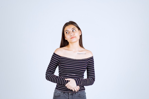 La chica con camisa a rayas se ve confundida y emocionada.