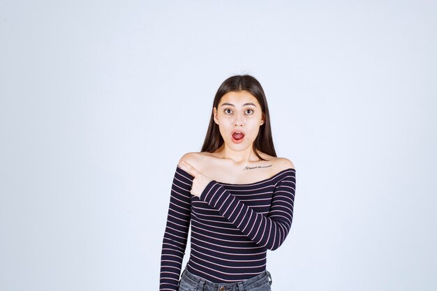 La chica con camisa a rayas se ve confundida y emocionada.