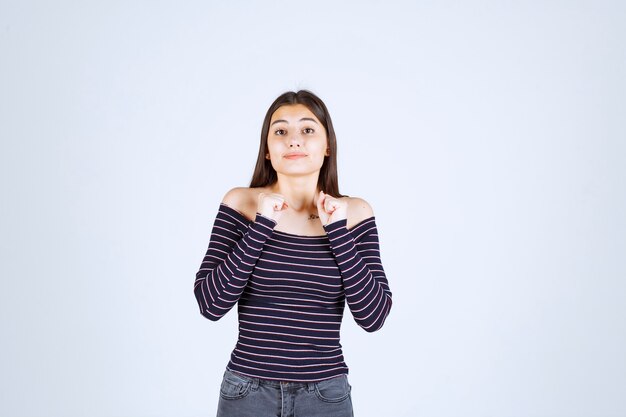 La chica con camisa a rayas se ve confundida y emocionada.