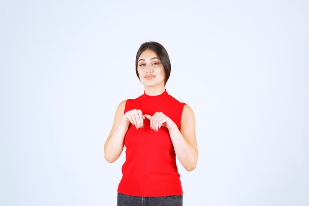 Chica con camisa roja apuntando hacia abajo.