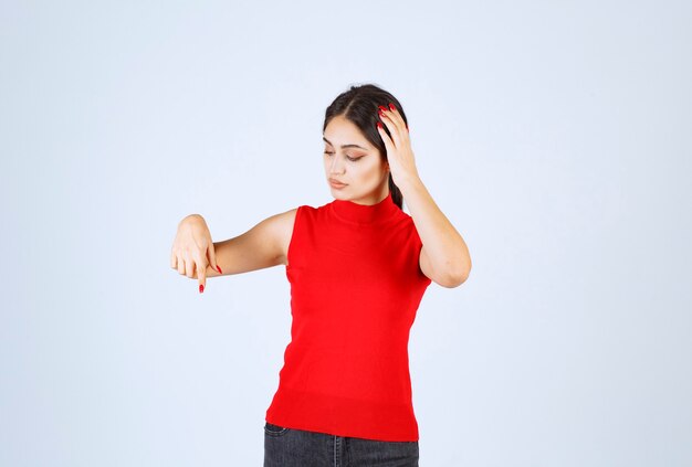 Chica con camisa roja apuntando hacia abajo.