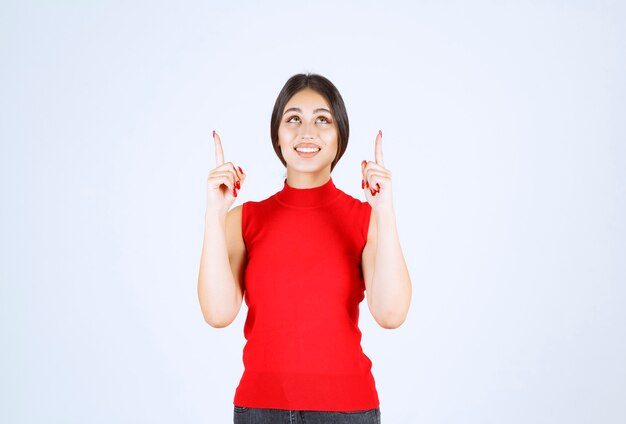 Chica de camisa roja apuntando al revés.