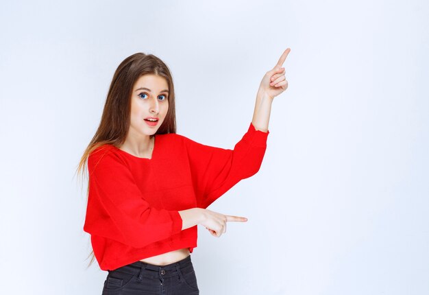 Chica de camisa roja apuntando al revés.