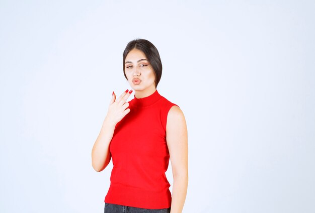 Chica en camisa roja dando poses encantadoras y seductoras.