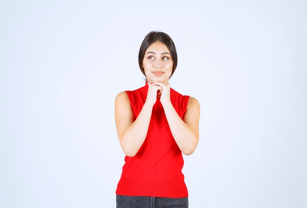 Chica con una camisa roja dando poses positivas y seductoras.