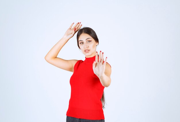 Chica con camisa roja deteniendo a alguien.