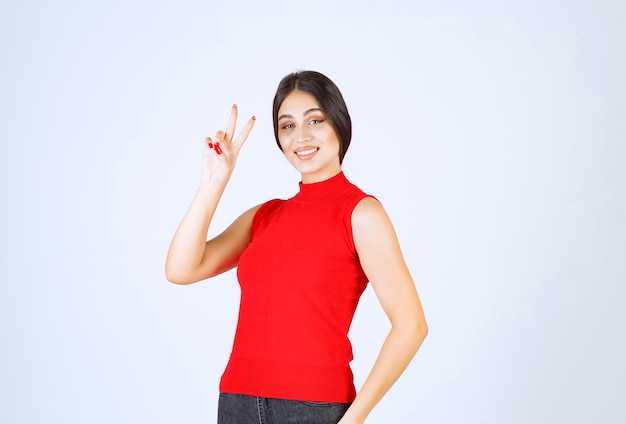 Chica de camisa roja enviando paz y amistad.