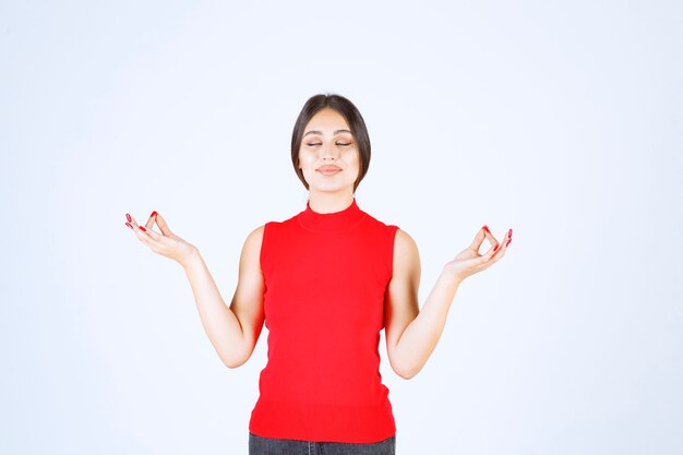 Chica de camisa roja haciendo meditación.