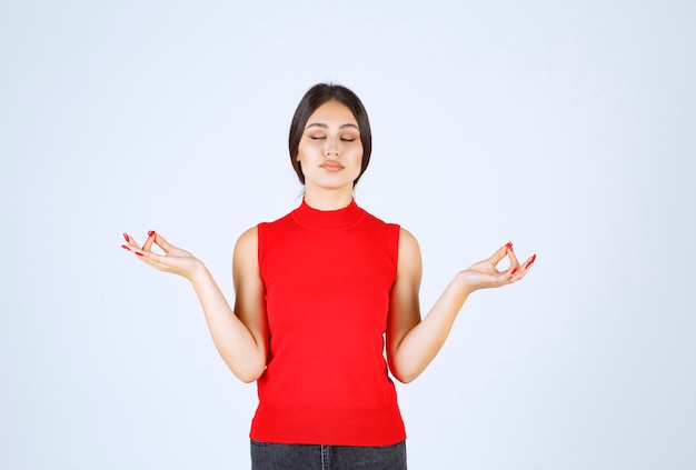 Chica de camisa roja haciendo meditación.