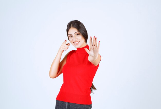 Chica de camisa roja impidiéndose algo.