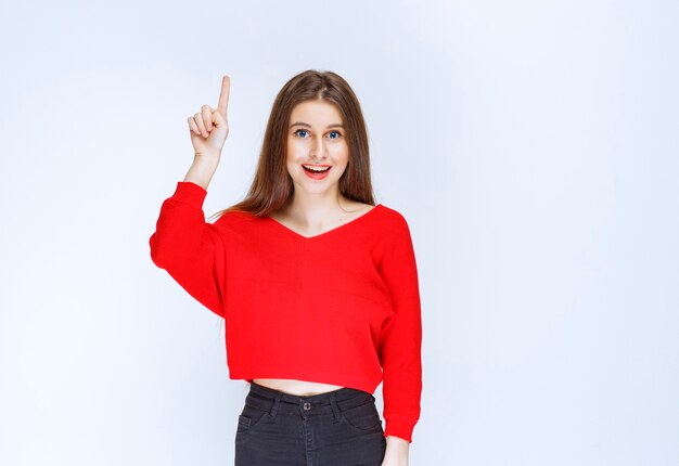 Chica en camisa roja mostrando algo al revés.