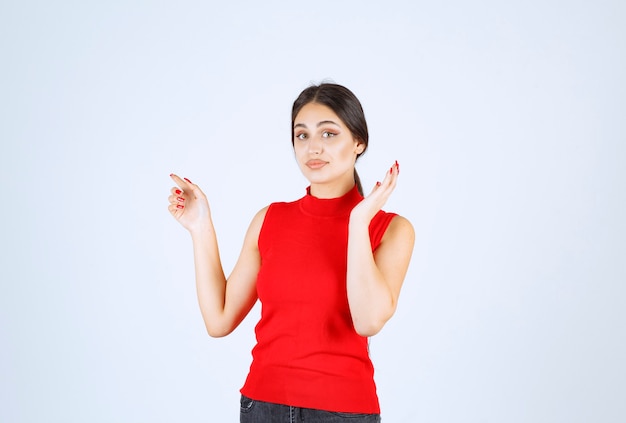 Chica con camisa roja mostrando algo a la izquierda.