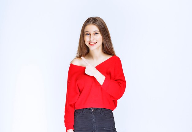 Chica con camisa roja mostrando algo en el lado izquierdo.