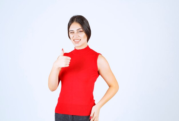 Chica con camisa roja mostrando los pulgares para arriba.