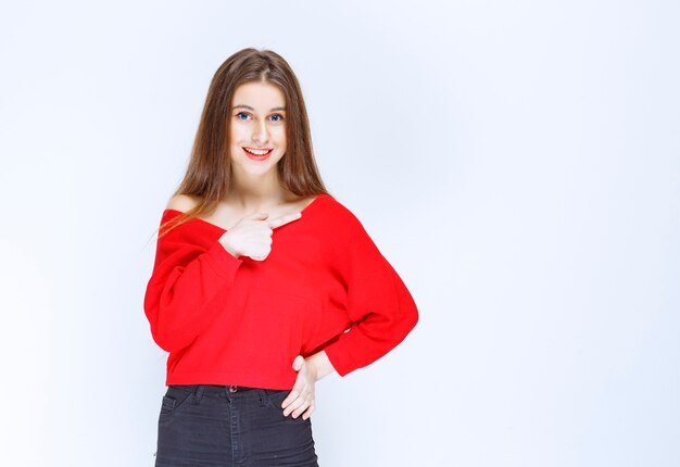 Chica en camisa roja mostrándose y sonriendo.