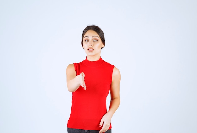 Foto gratuita chica en camisa roja notando a alguien adelante y saludándolo.
