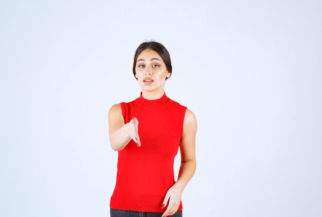 Chica en camisa roja notando a alguien adelante y saludándolo.