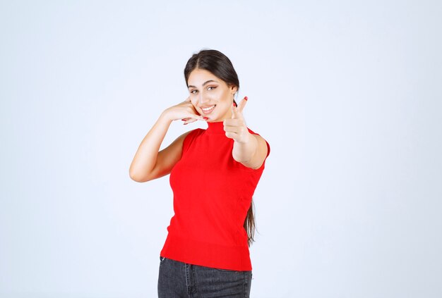 Chica en camisa roja notando a alguien adelante y saludándolo.