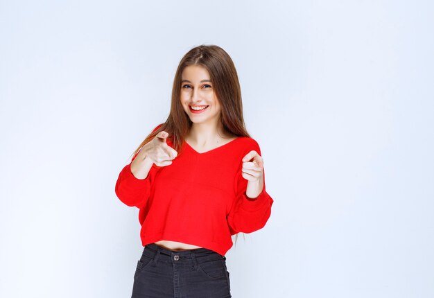 Chica de camisa roja notando a la persona que está delante.