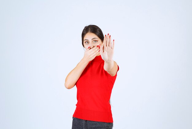 Chica con una camisa roja parando algo con las manos.