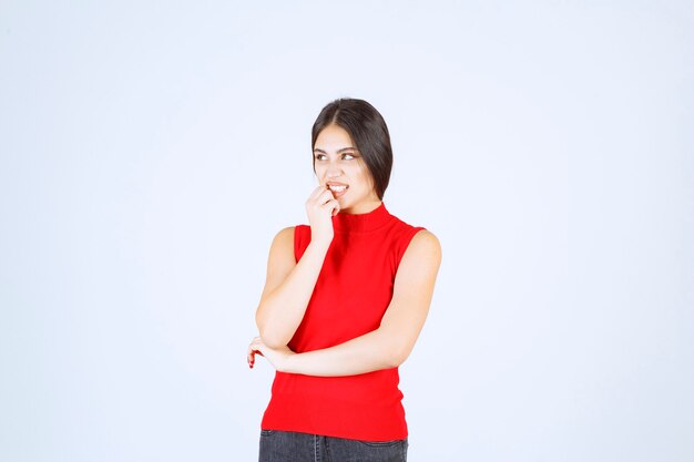 La chica con una camisa roja parece asustada y aterrorizada.