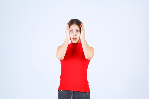 La chica con una camisa roja parece asustada y aterrorizada.