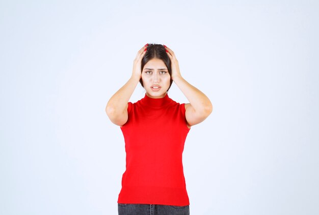 La chica con una camisa roja parece asustada y aterrorizada.