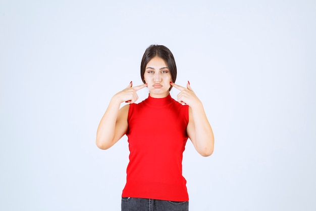 Chica de camisa roja pensando y refrescando su mente.