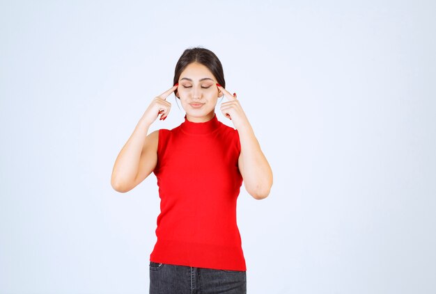 Chica de camisa roja pensando y refrescando su mente.