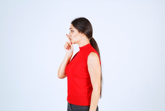 Chica de camisa roja pidiendo silencio.