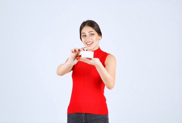 Chica en camisa roja presentando su tarjeta de visita.