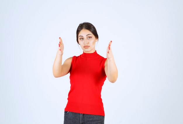 Chica de camisa roja que muestra la dimensión de un objeto.