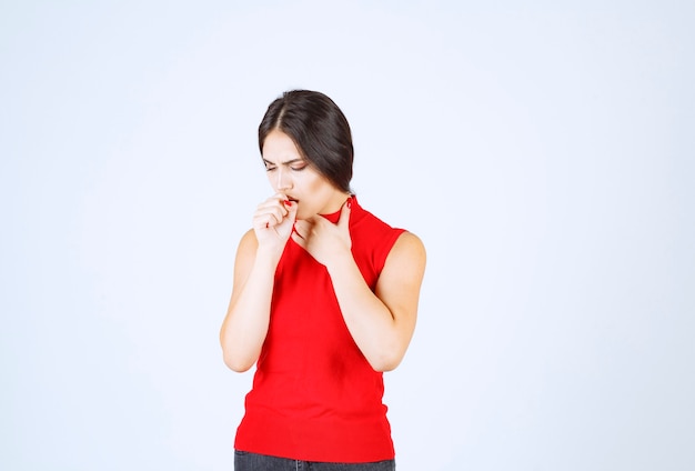 Chica con camisa roja se siente fría y enferma.