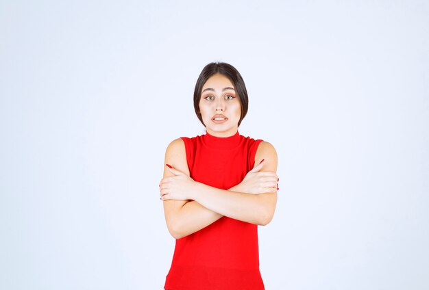 Chica con camisa roja se siente fría y enferma.