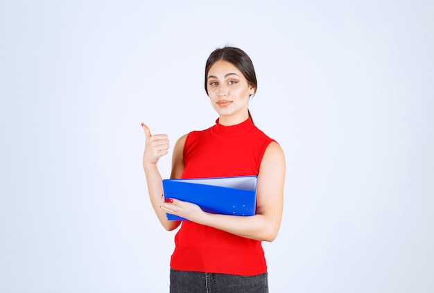 Chica de camisa roja sosteniendo una carpeta de negocios azul.