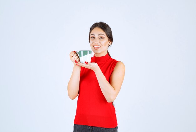 Chica de camisa roja sosteniendo una taza de café.